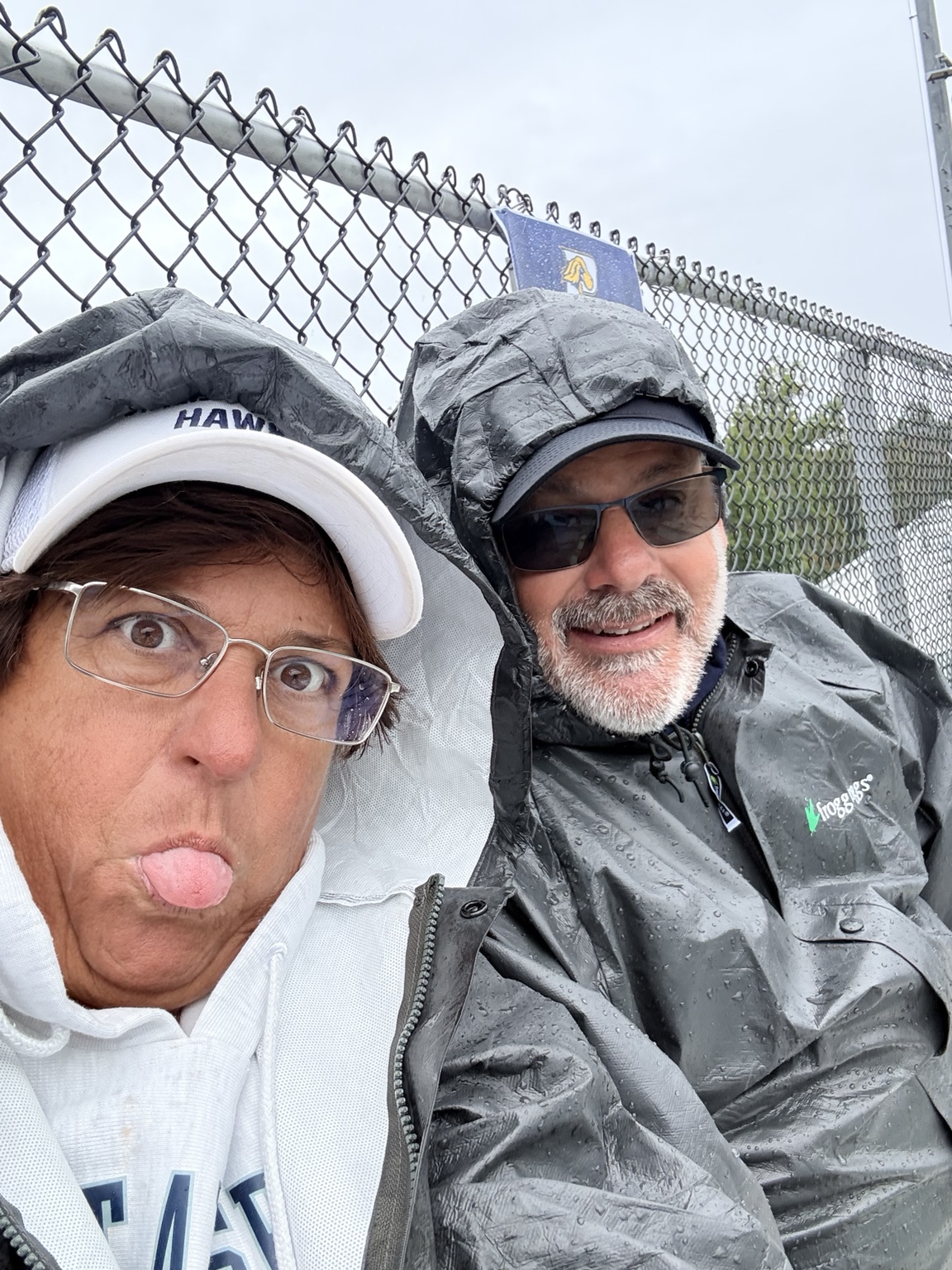 Hawks families smiling beneath umbrellas in the rain